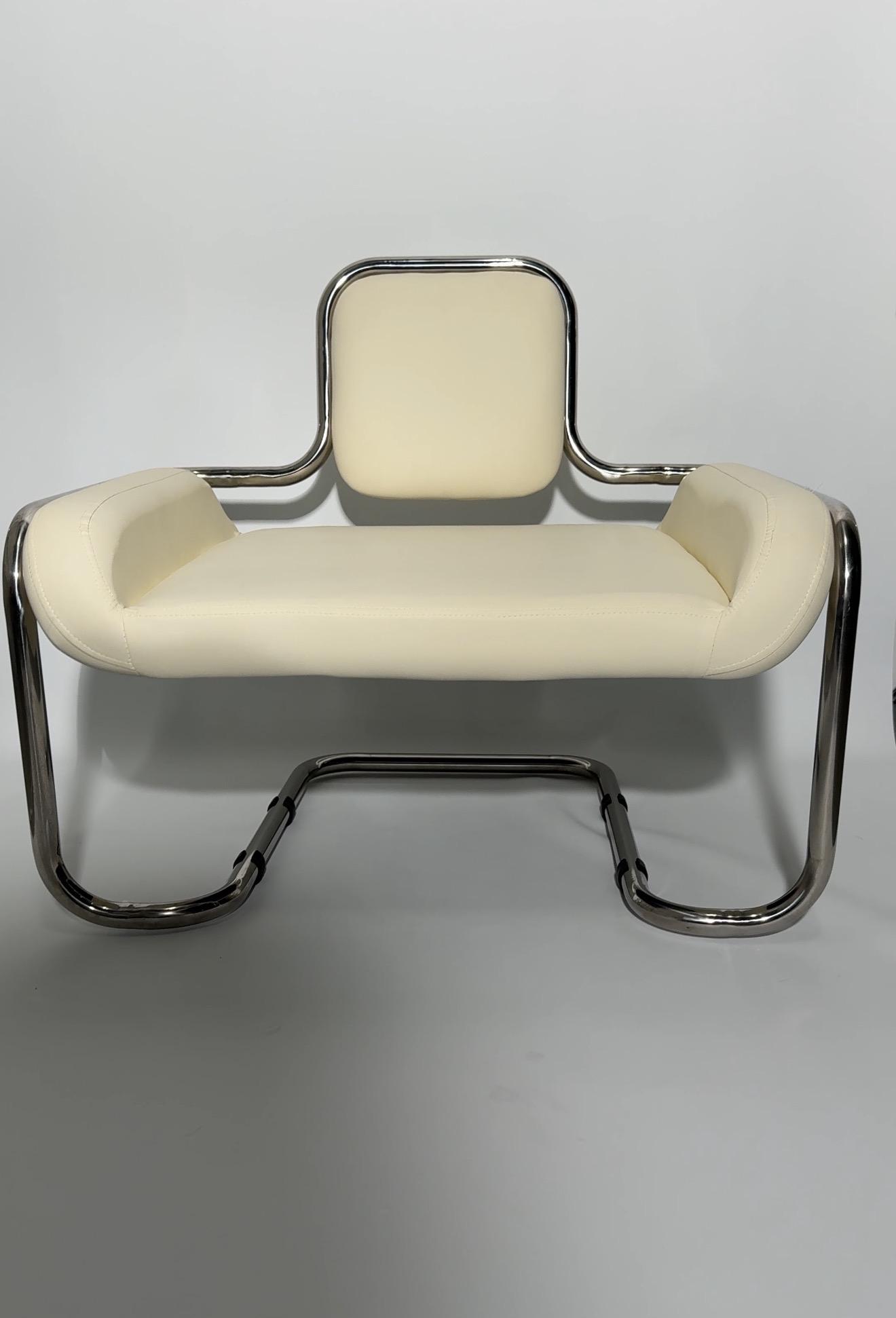 Cream upholstered bench wrapped in a tubular chrome frame.