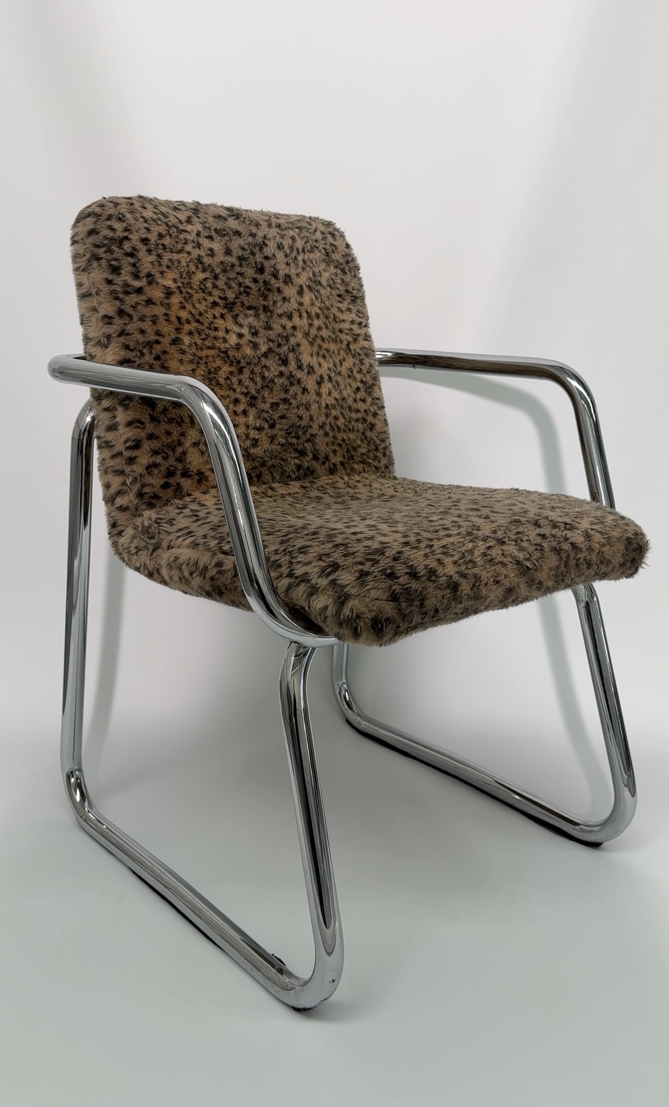 Cheetah print bouclé chair, three-quarter angle, chrome sled base.