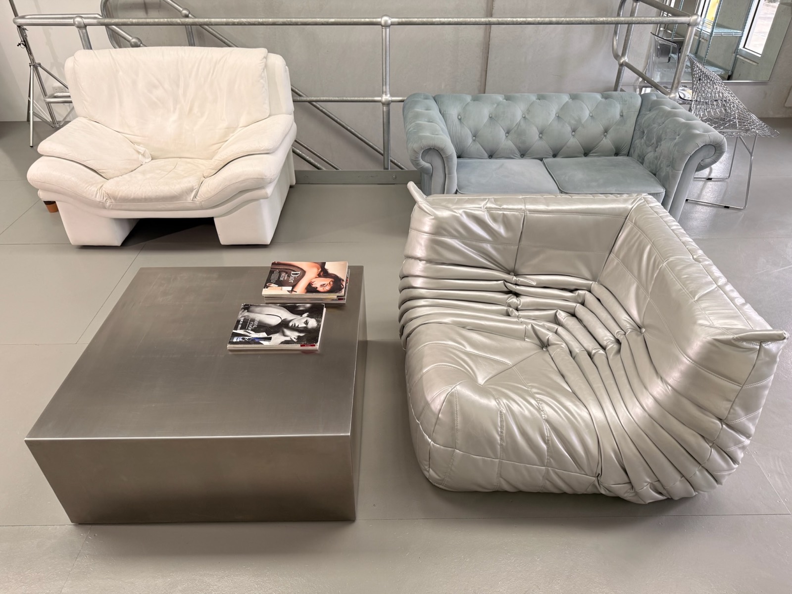 Silver Togo lounges and a chesterfield around a brushed-metal coffee table.